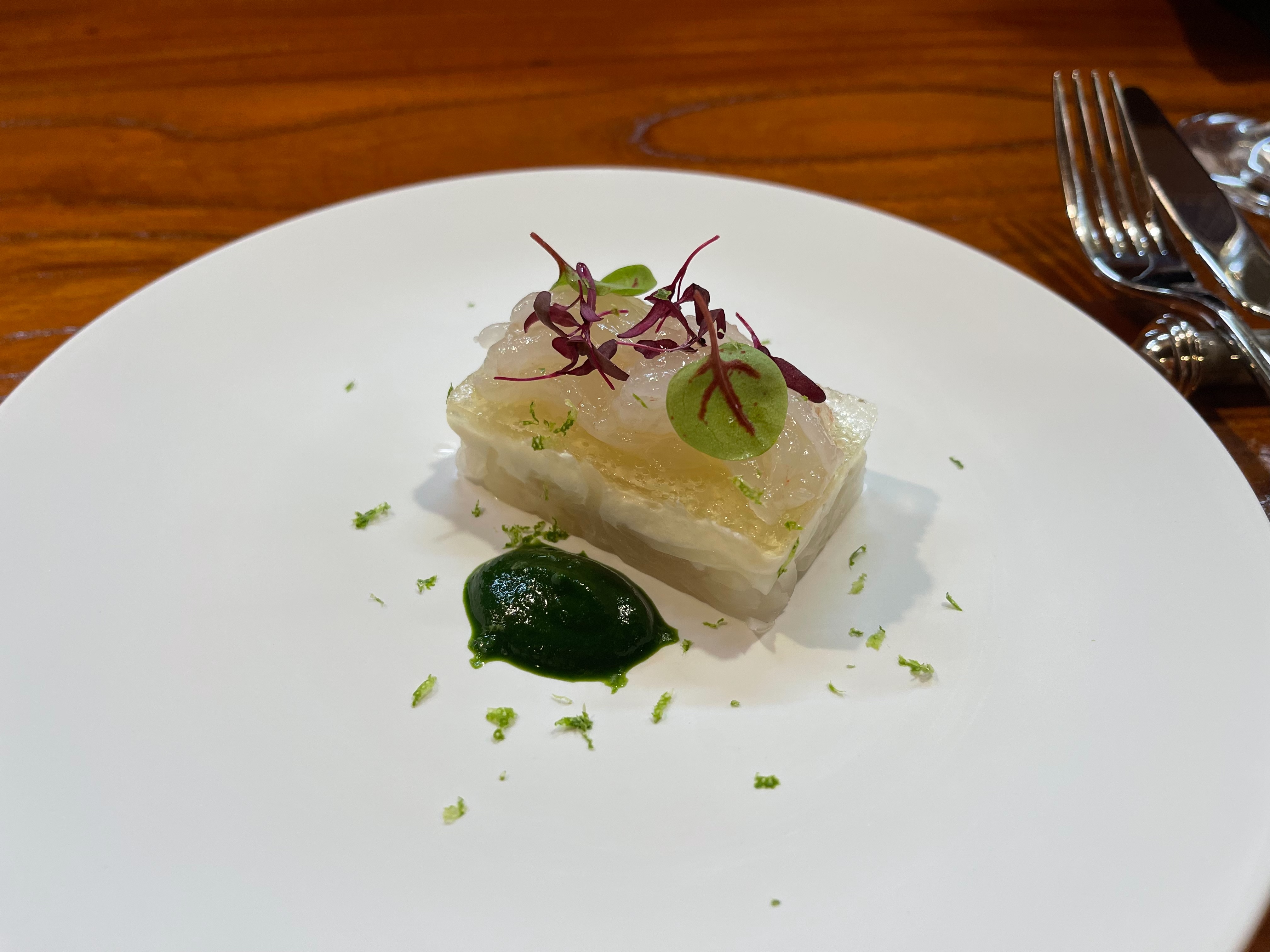 白い皿に盛られた層状の料理と緑のソース