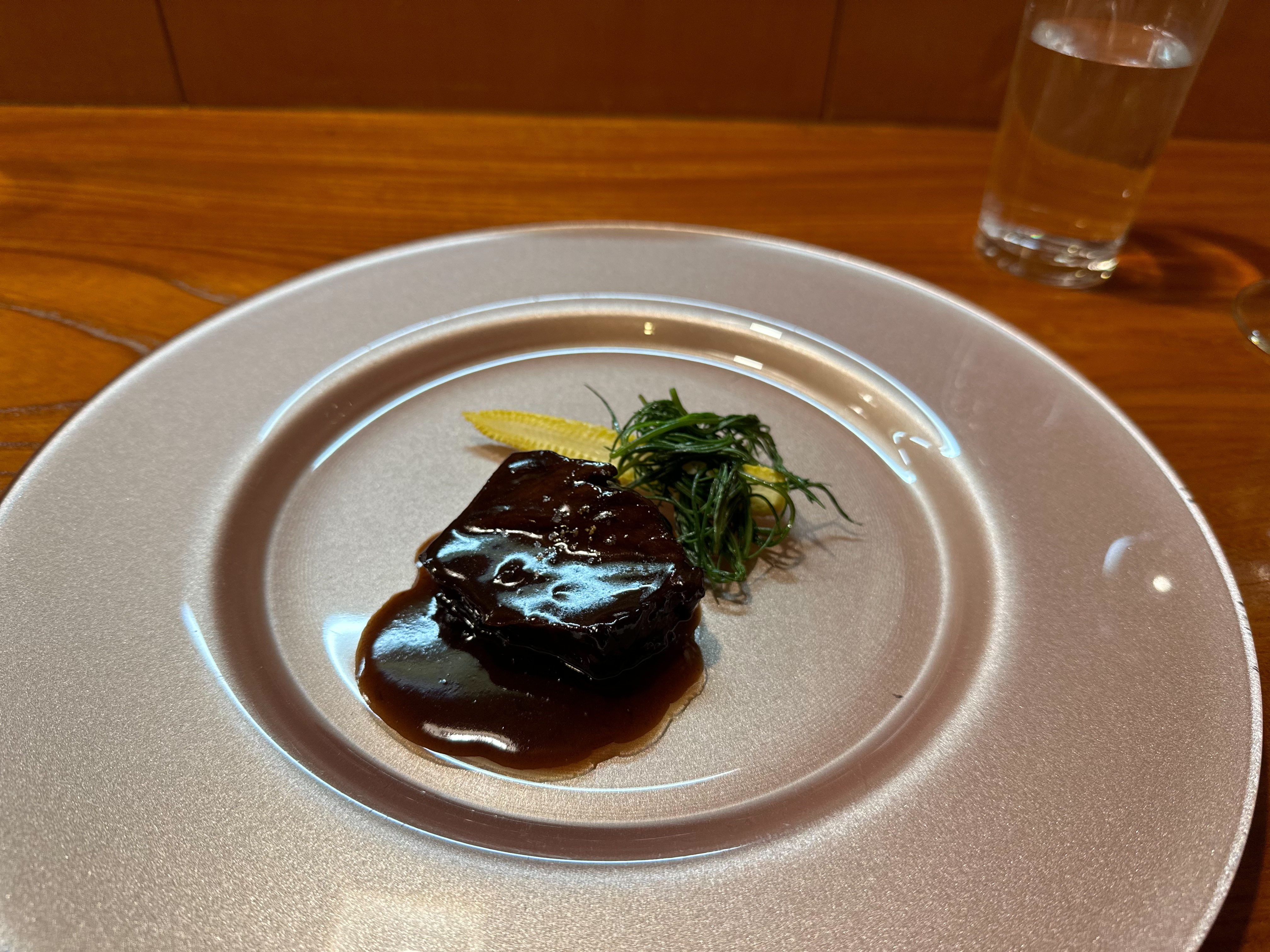 濃い赤褐色のソースをまとった肉料理と付け合わせ